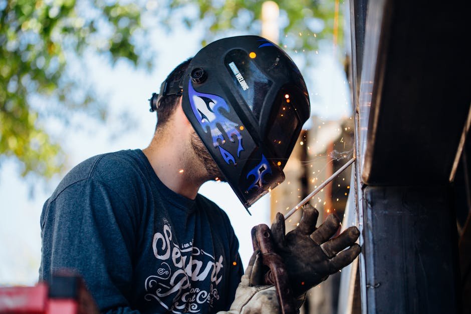A skilled welder working outside, producing sparks. Shows focus and safety.